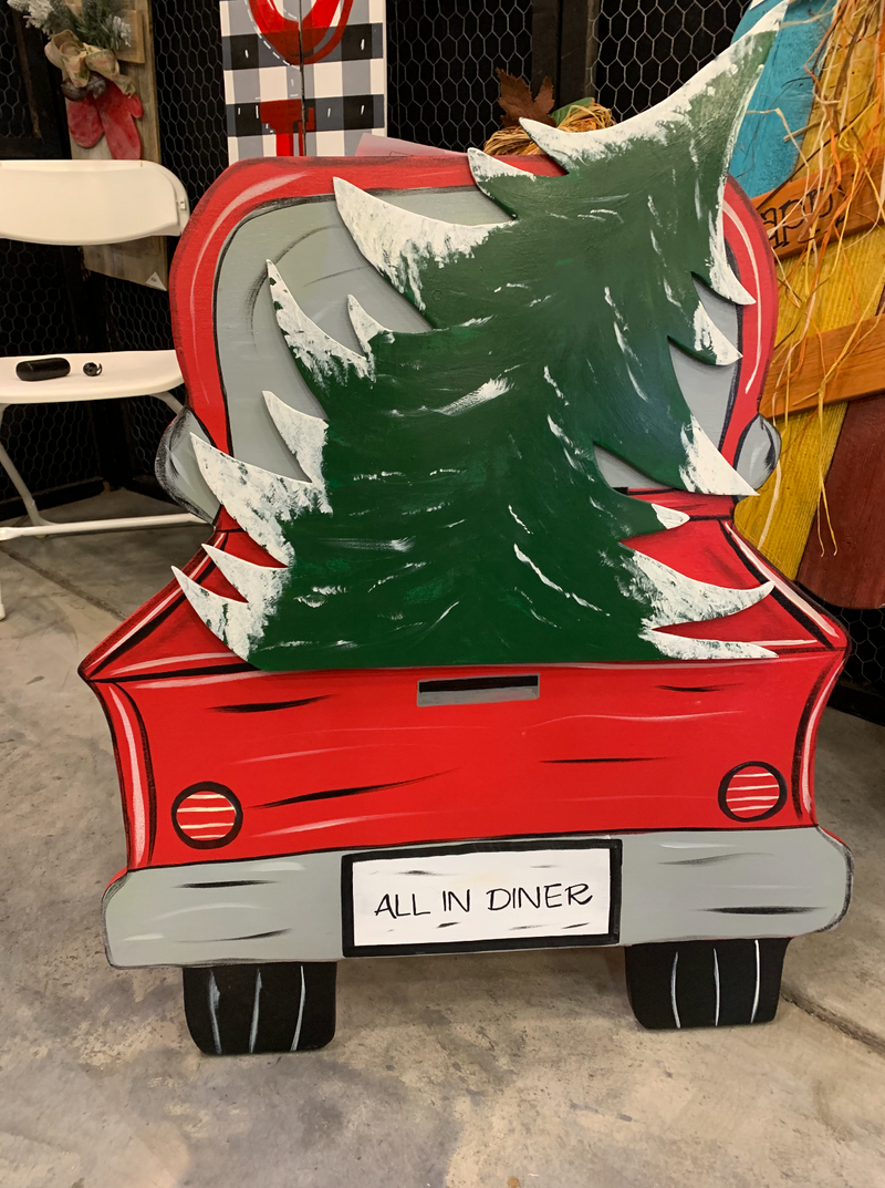 Decorative sign of a red truck with a Christmas tree in the back, featuring 'All in Diner' text.